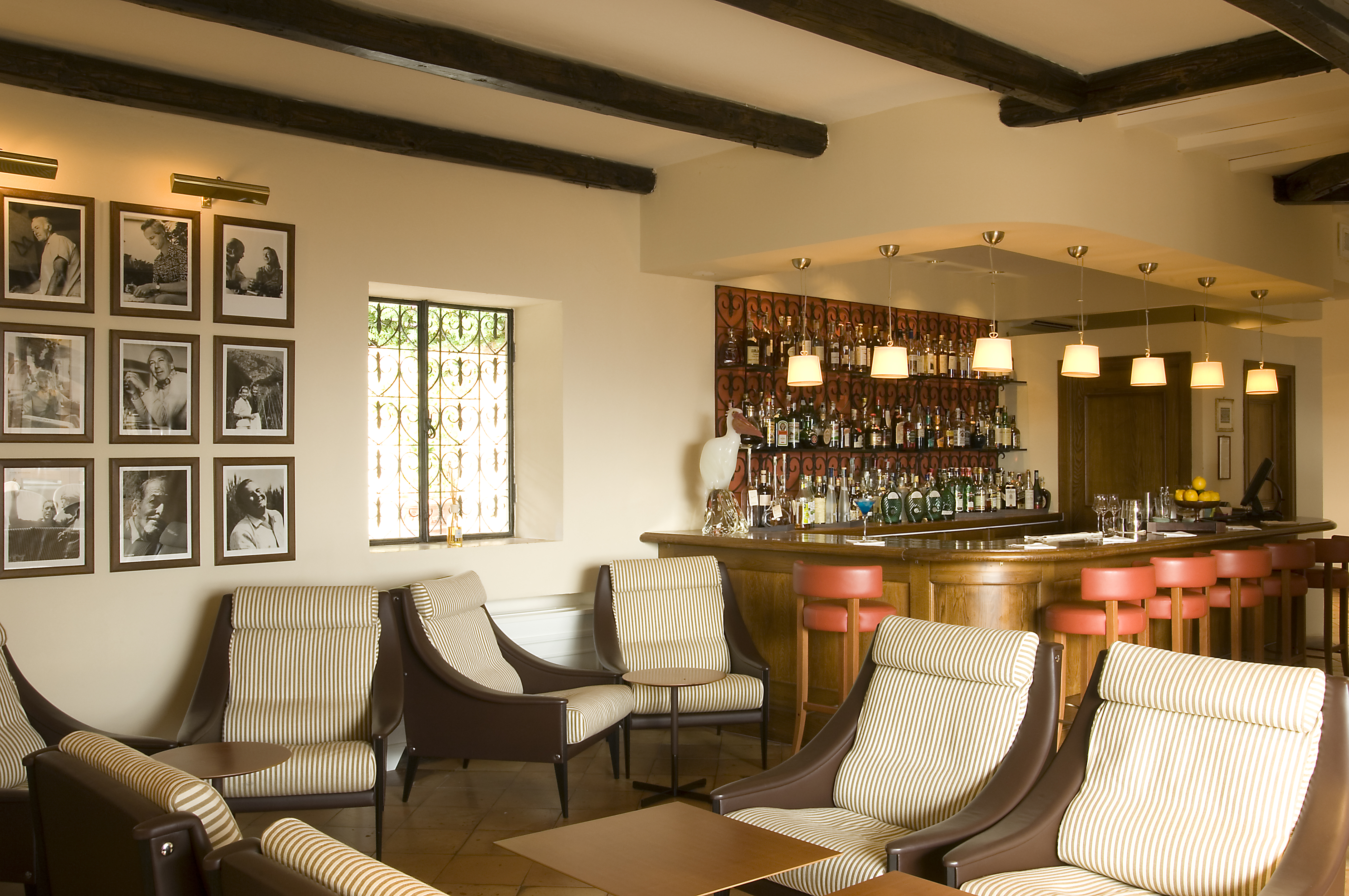 Indoor bar with photos on the wall, cushioned seats and a wood pannelled bar area with drinks behind