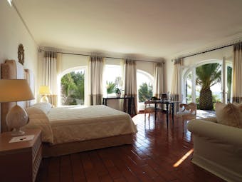 Suite with sea view, wood pannelled floors, large double bed, sofa and balcony