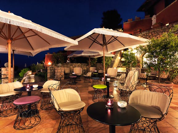 Outdoors terrace bar with seats and tables set up beneath umbrellas