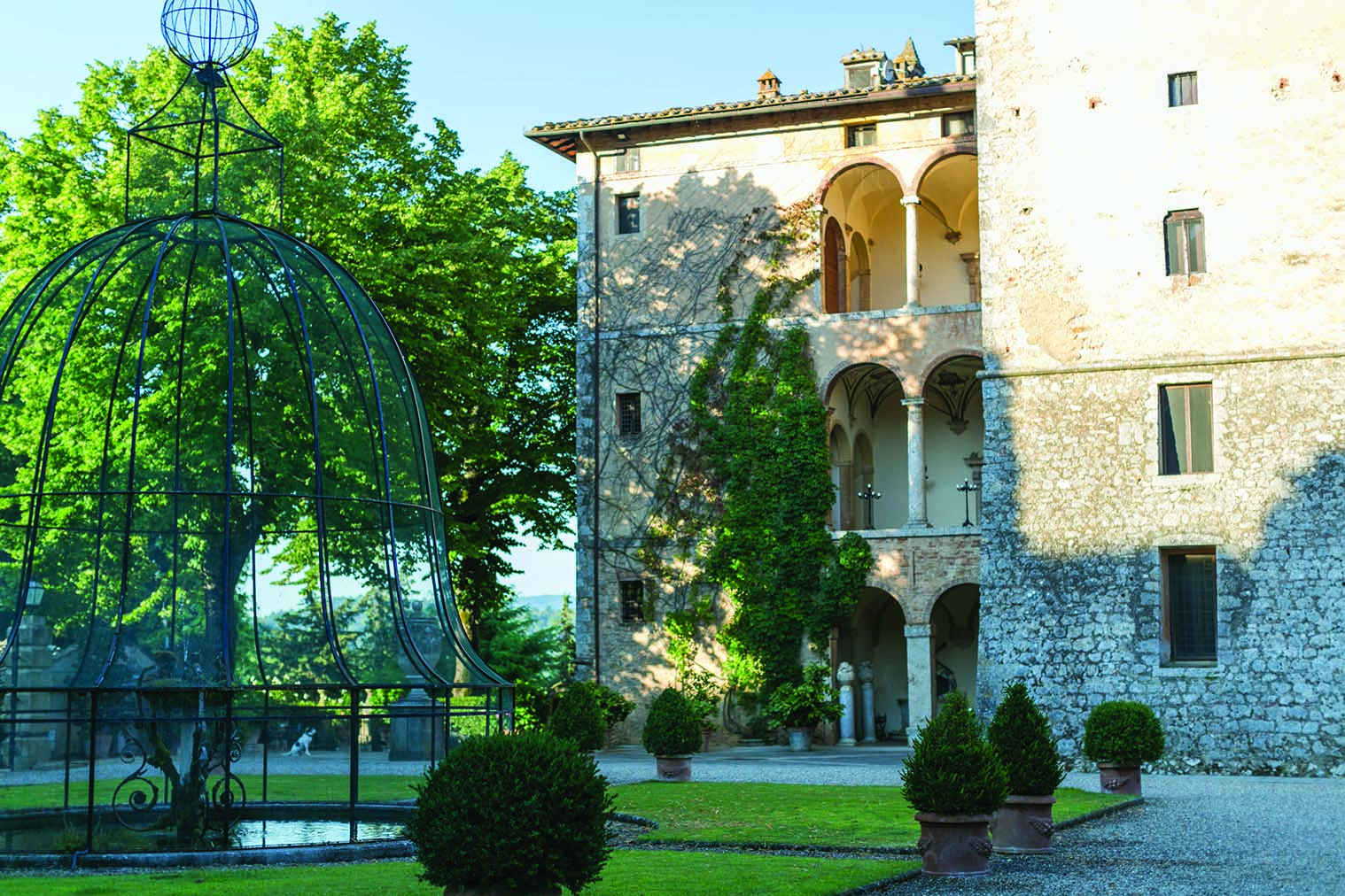 View of the exterior of the Relais La Suvera with a stone building with arched window and greenery outside