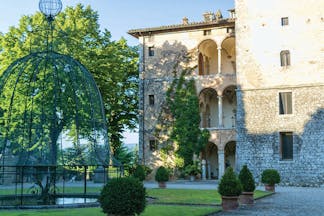 View of the exterior of the Relais La Suvera with a stone building with arched window and greenery outside