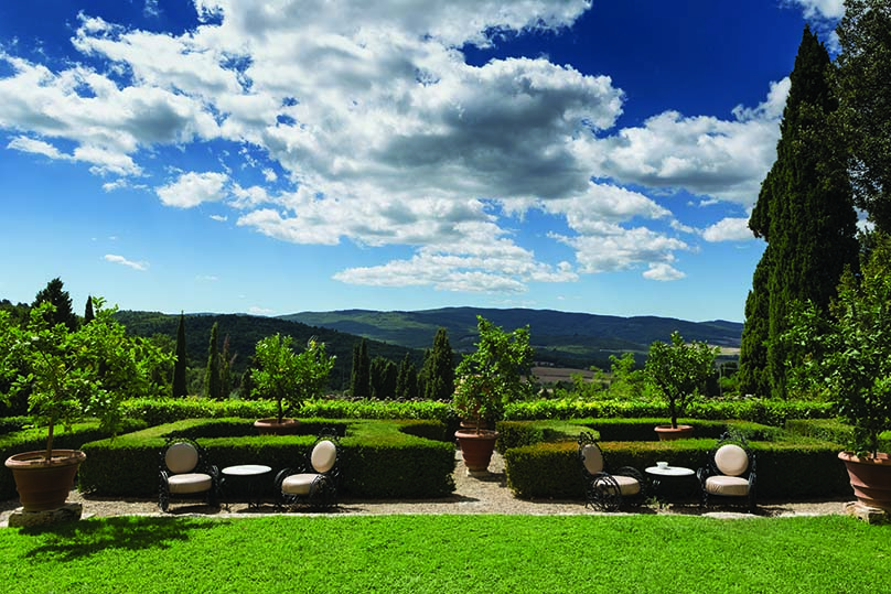 View of the gardens at the Relais la Suvera with neatly shaped hedges and chairs set out 