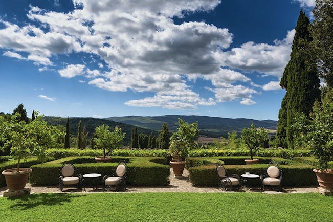 View of the gardens at the Relais la Suvera with neatly shaped hedges and chairs set out 