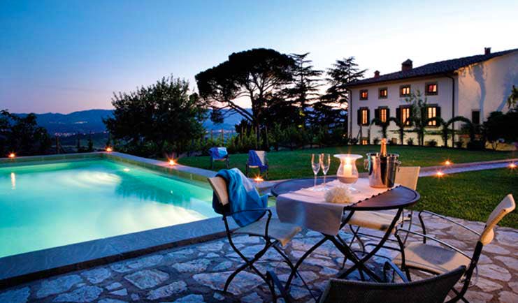 Swimming pool with table set up on the edge and light glowing