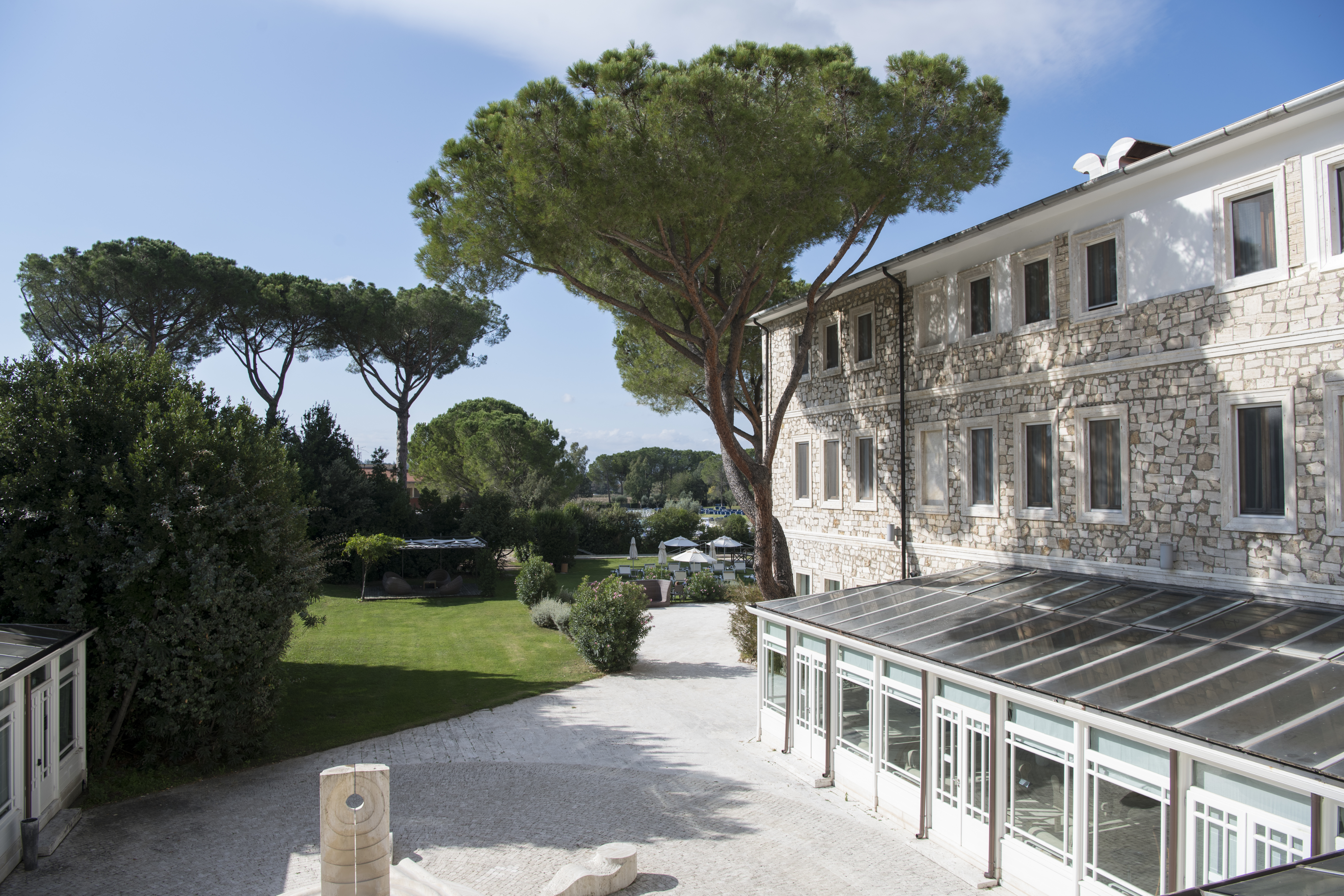 Umbrella pines and stone building with courtyard
