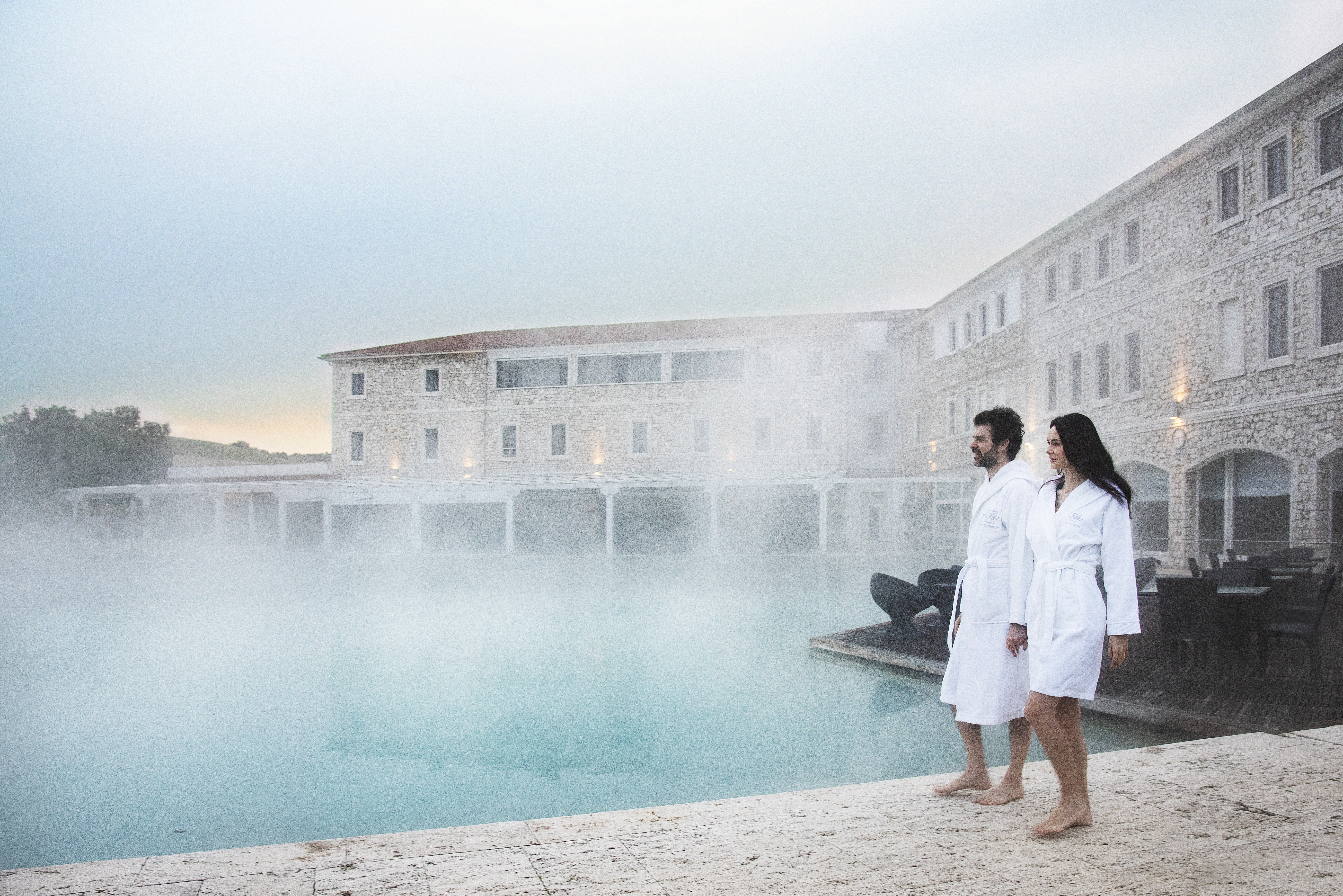 Thermal pool with steam in cold air and two people