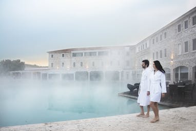 Thermal pool with steam in cold air and two people