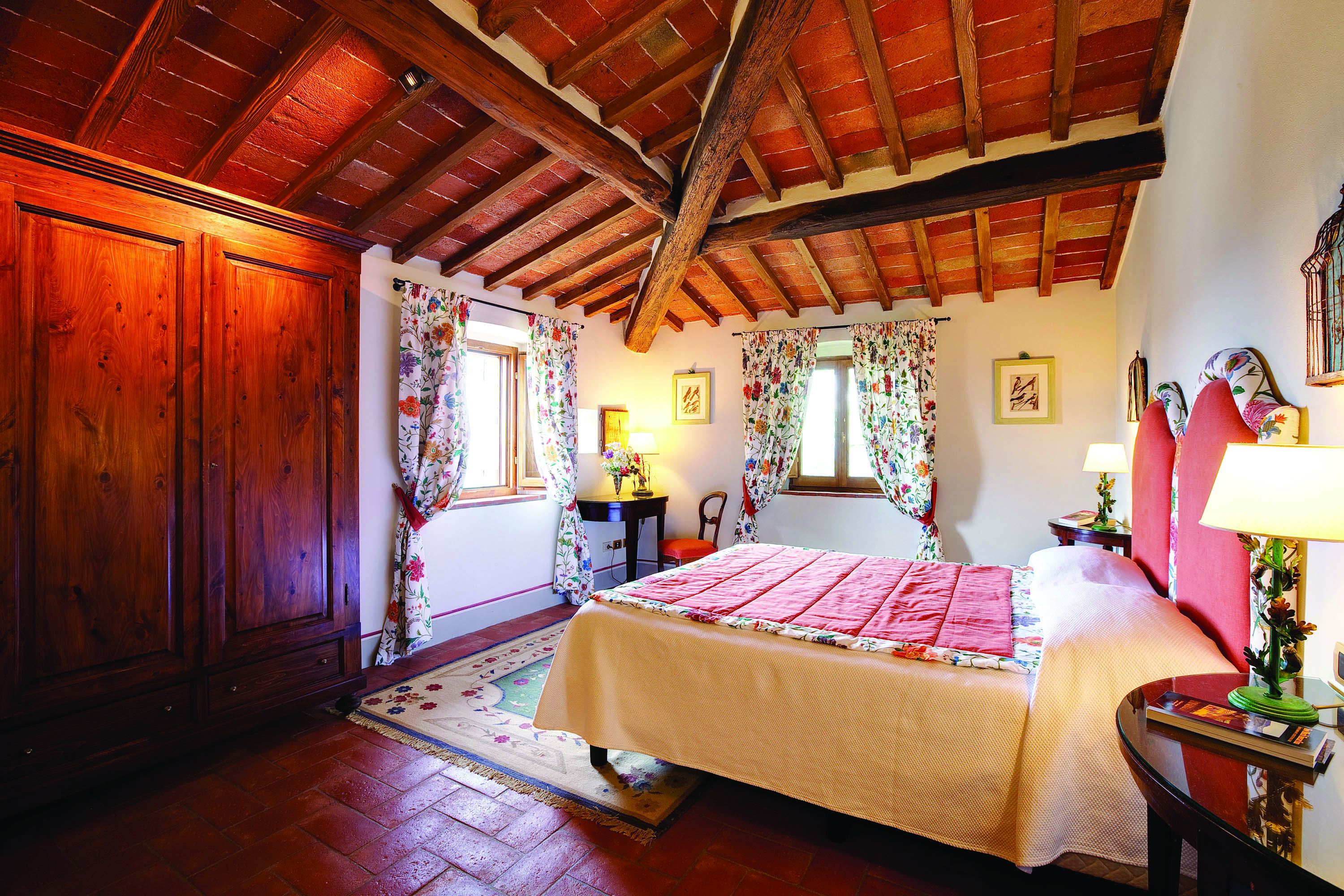 Bedroom with wood pannelled ceilings and floors, floral patterned curtains and double bed 