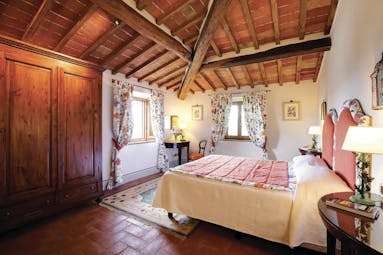 Bedroom with wood pannelled ceilings and floors, floral patterned curtains and double bed 