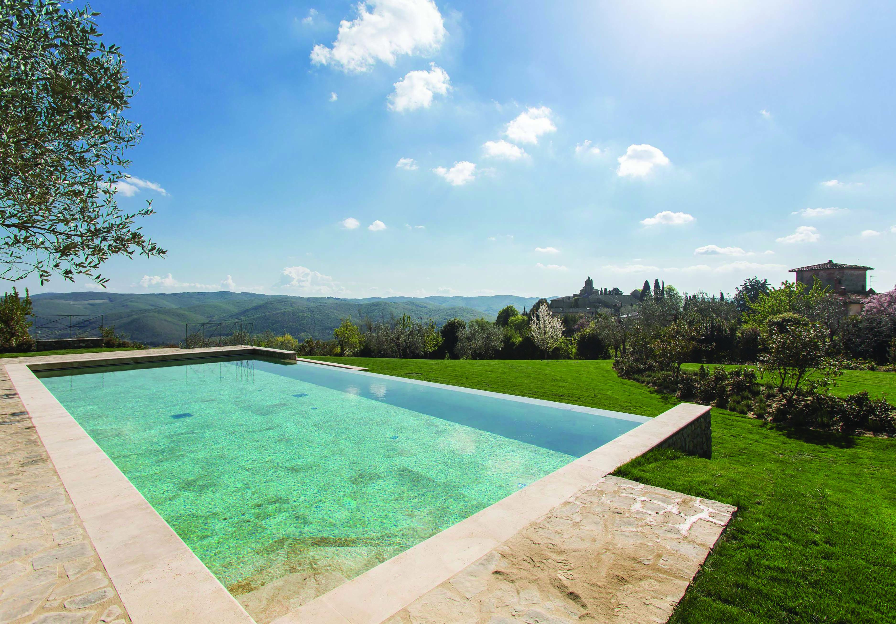 Heated infinity pool in travertine marble looking out over grassy mountains and trees