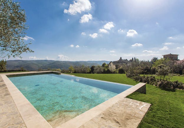 Heated infinity pool in travertine marble looking out over grassy mountains and trees