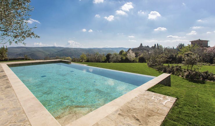 Heated infinity pool in travertine marble looking out over grassy mountains and trees