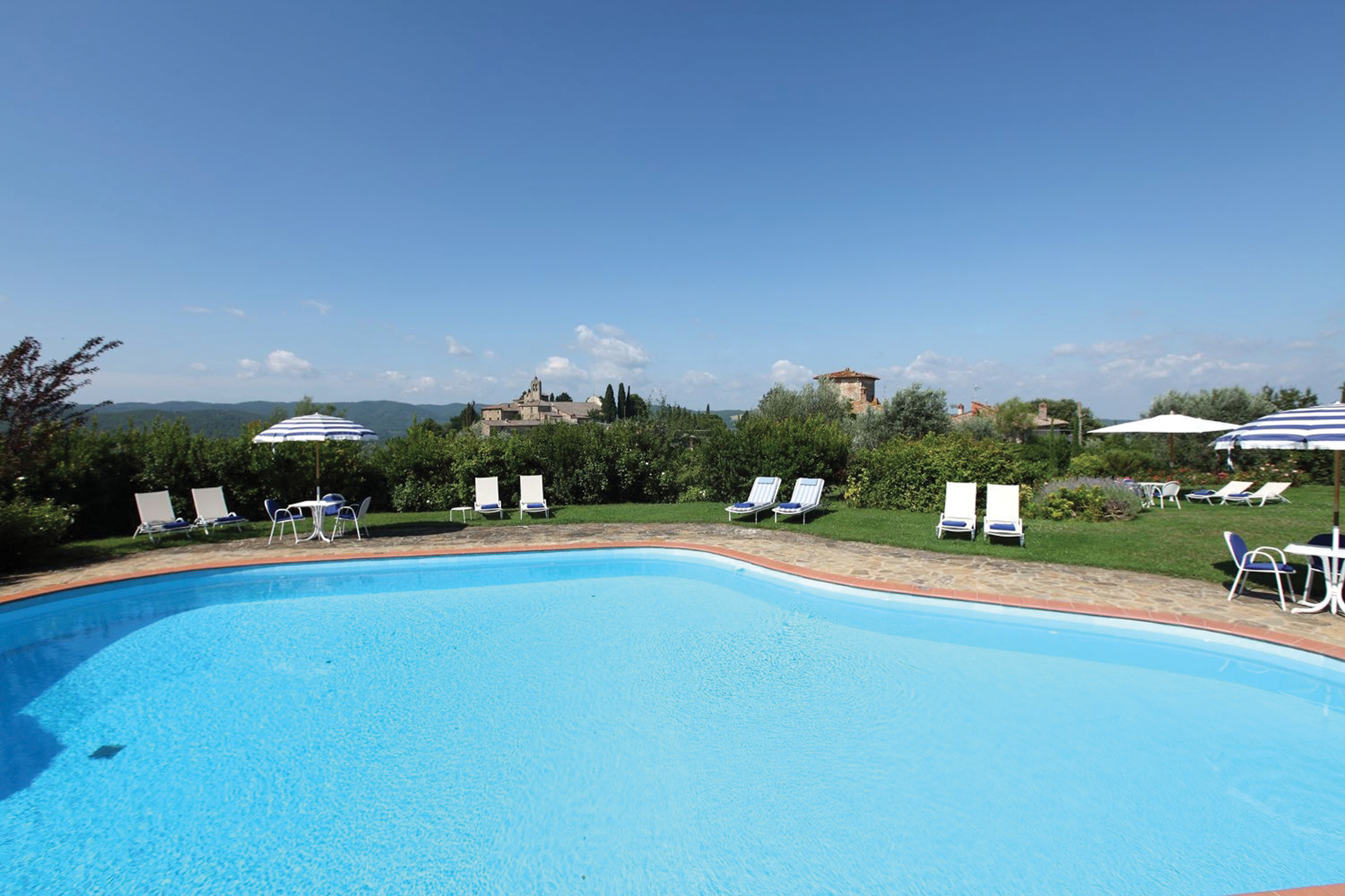Main swimming pool with blue and white striped sun beds and umbrellas around the edge of the pool 