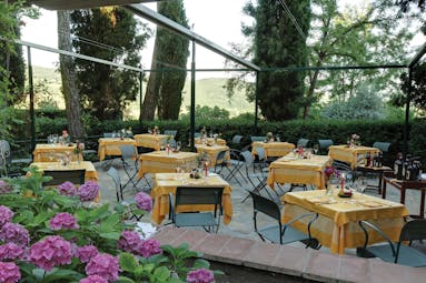 Outdoor dining terrace with flowers around and tables set up with a yellow table cloth