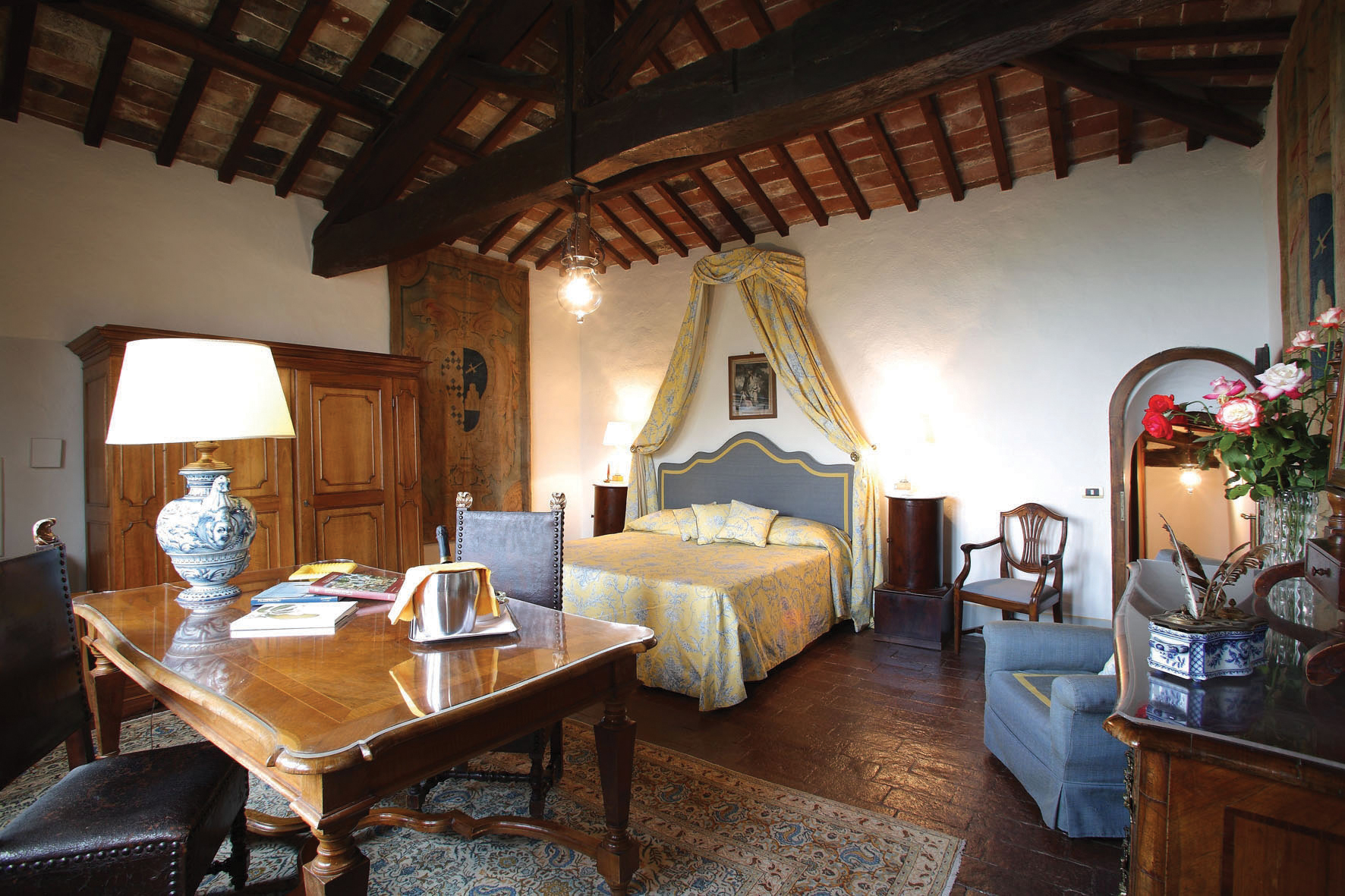 Tower bedroom with wood pannelled floor and ceiling, double bed with yellow drapes and desk table