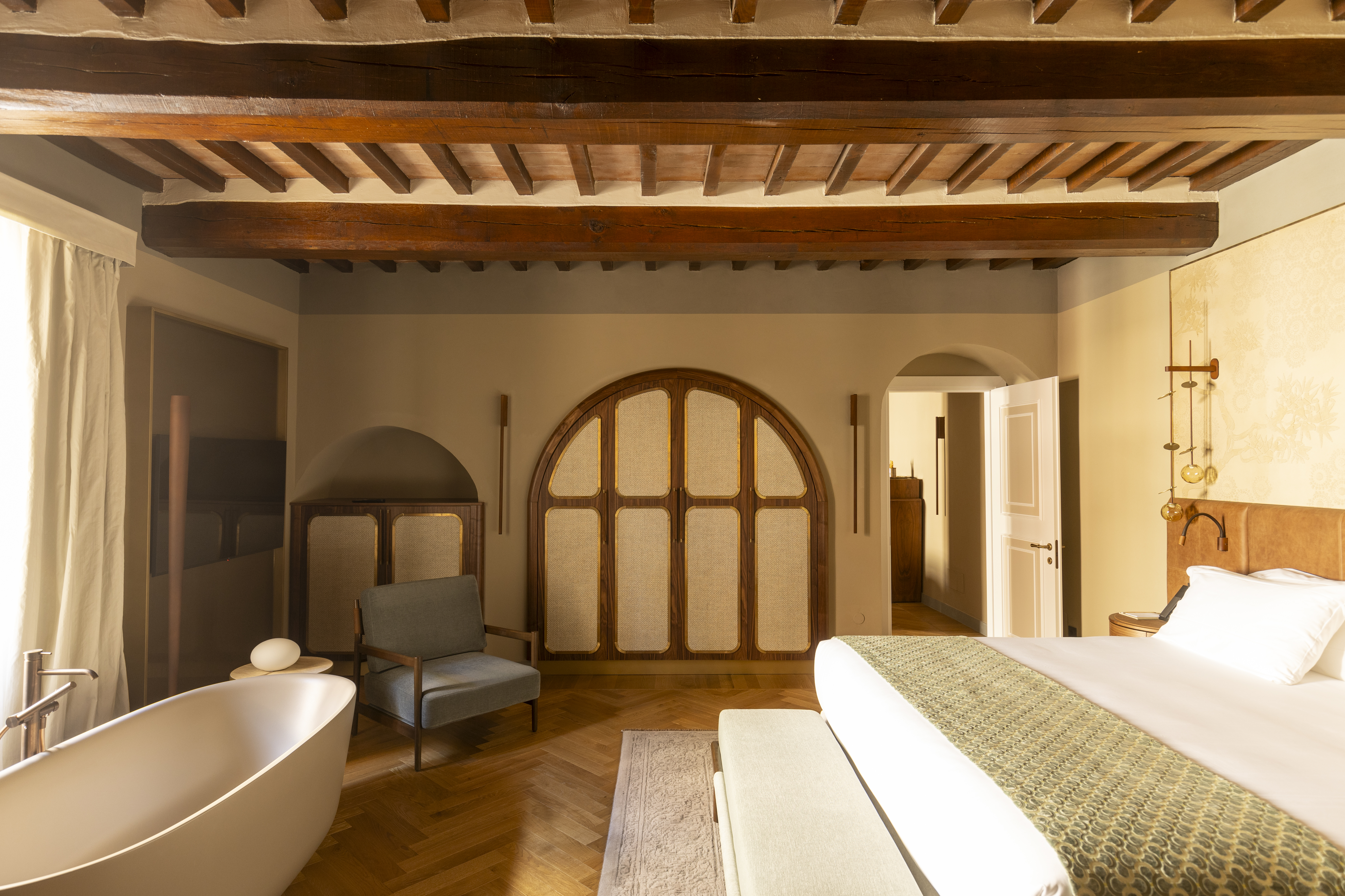 Borgo dei Conti Cloister Suite, with beamed ceilings, warm neutral colour palette, and freestanding bathtub