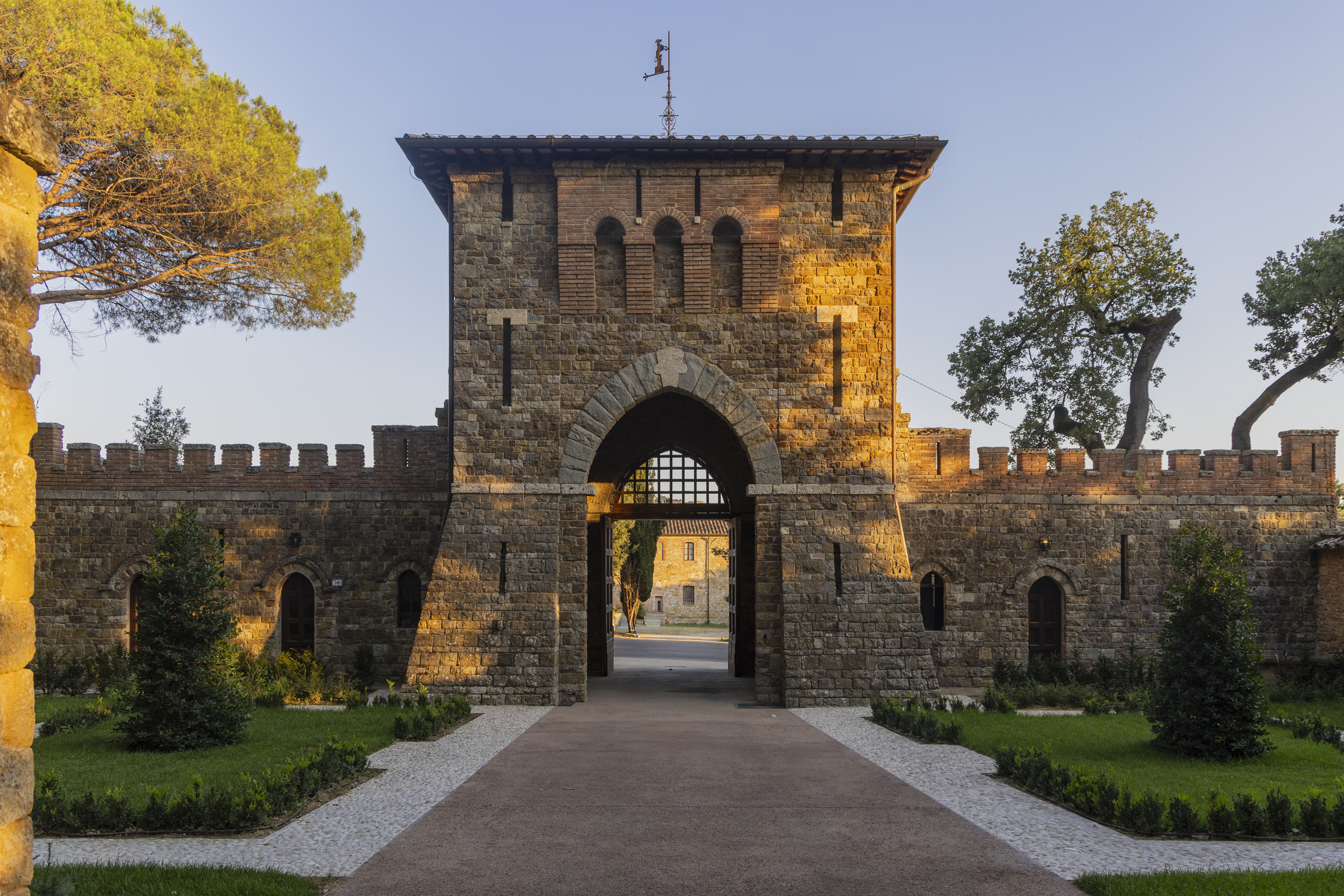 Borgo dei Conti entrance, with huge stone gate and castle walls, and landscaped gardens on either side