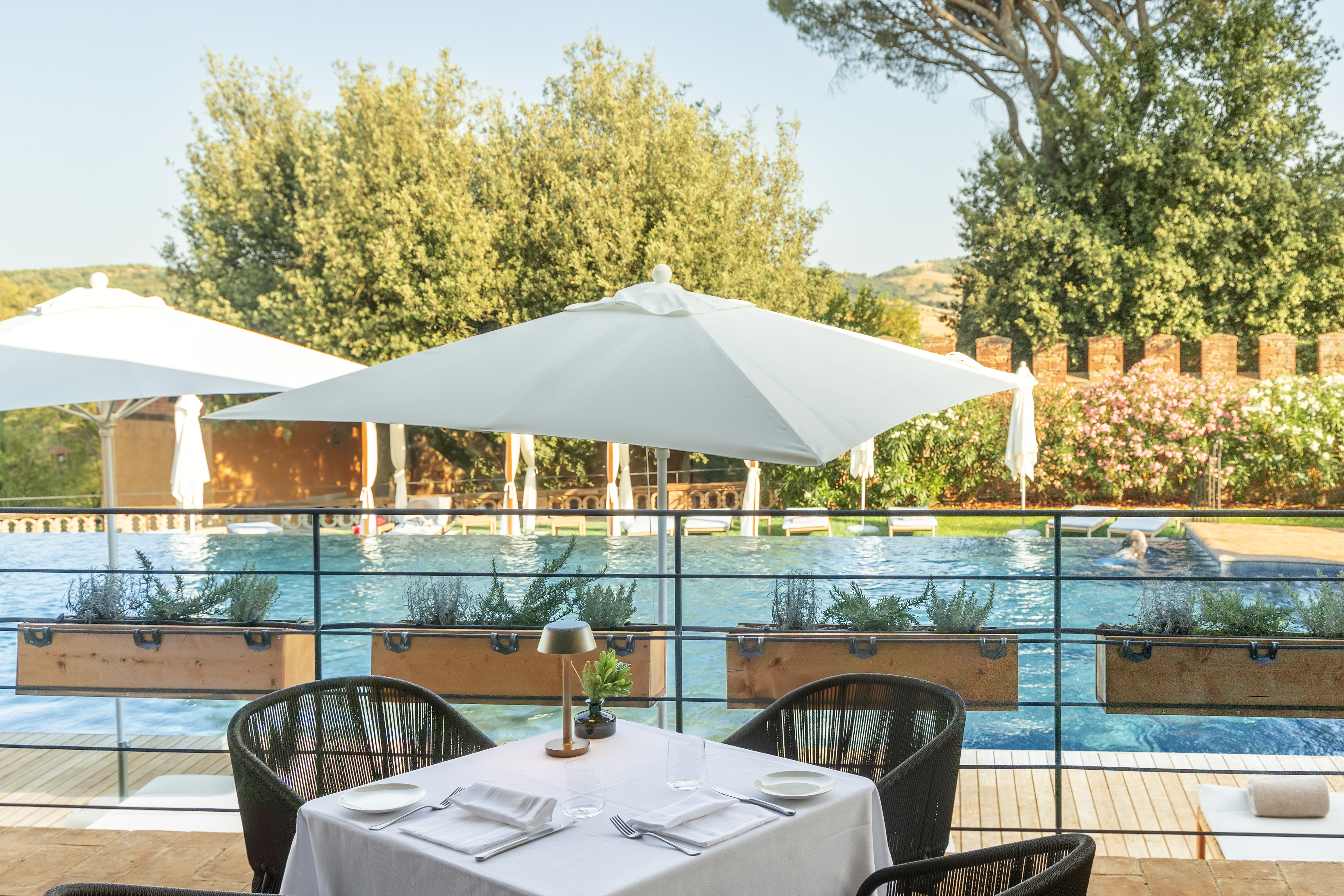 Borgo dei Conti Osteria del Borgo, with tables and chairs on a deck overlooking the poolside