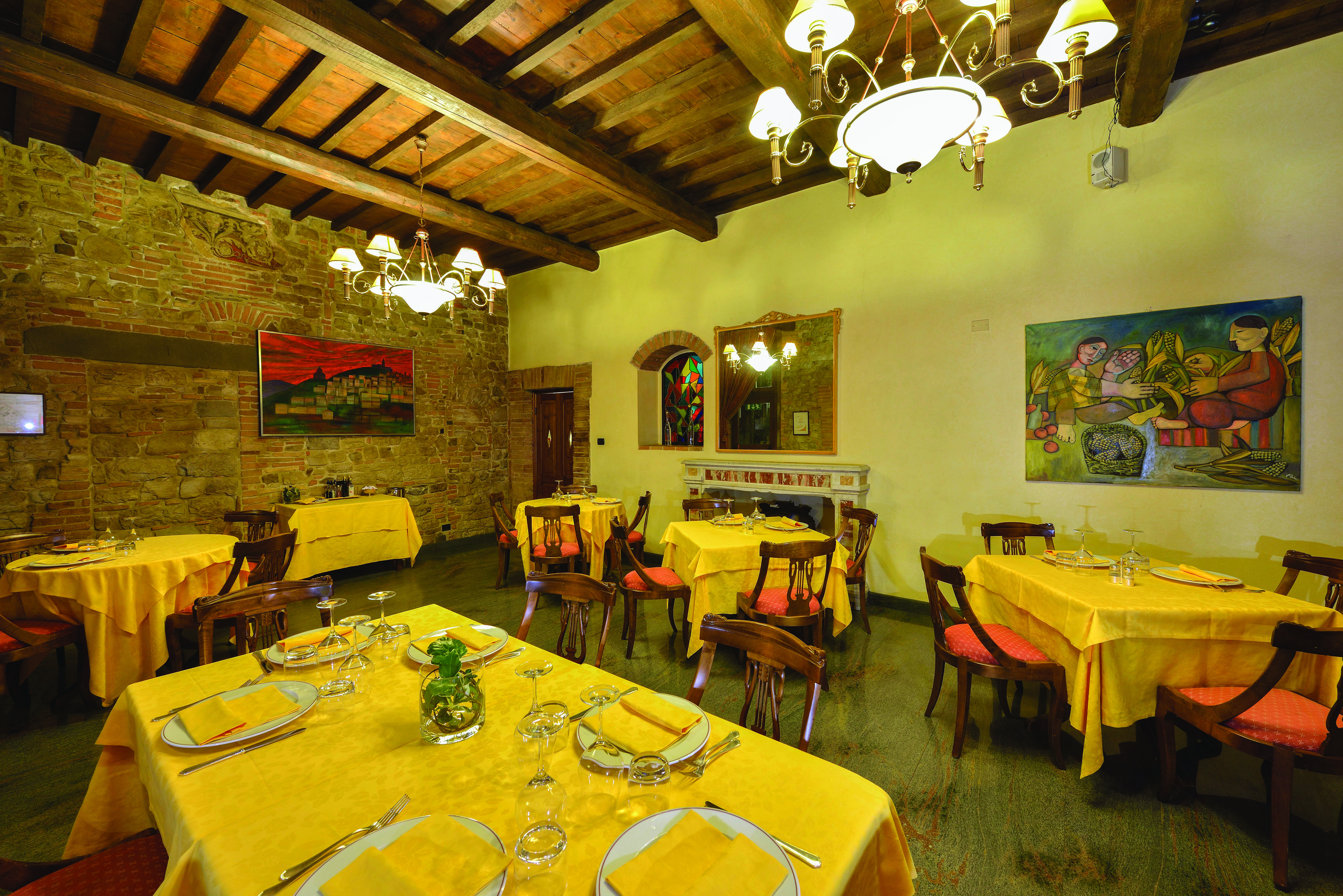 Another indoor dining area with yellow table cloths, wooden ceiling panels and chairs