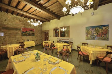 Another indoor dining area with yellow table cloths, wooden ceiling panels and chairs