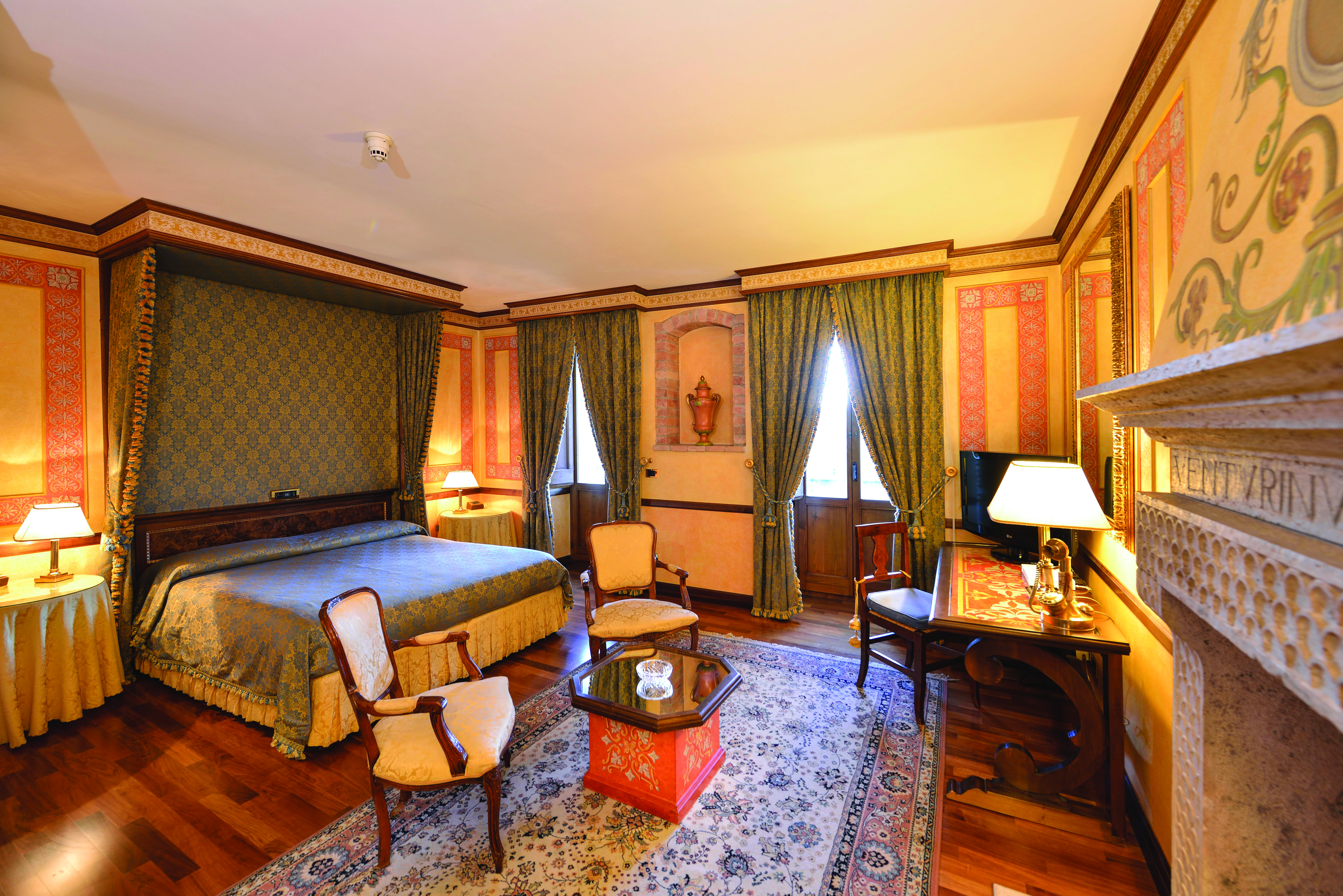 Hotel Fonte Cesia suite with large double bed, fireplace, desk and armchairs 