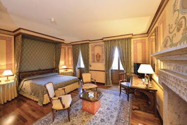 Hotel Fonte Cesia suite with large double bed, fireplace, desk and armchairs 