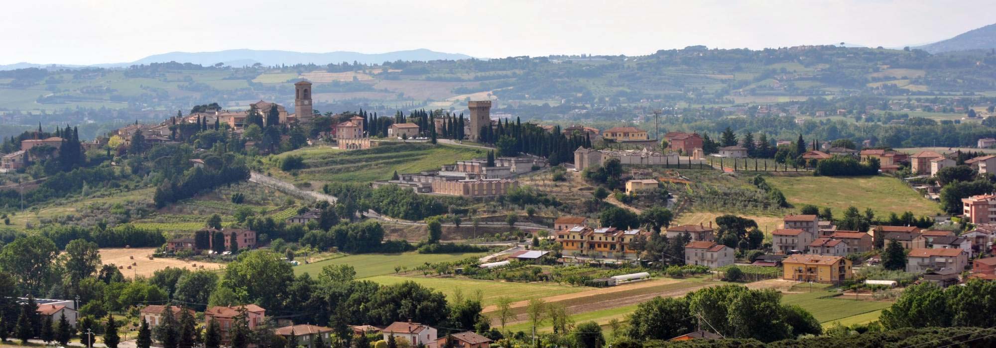 View of village on hill with green fields and hilds