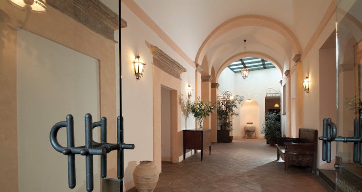 Entrance to hotel with large archway and wall lamps lighting the way 