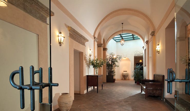 Entrance to hotel with large archway and wall lamps lighting the way 