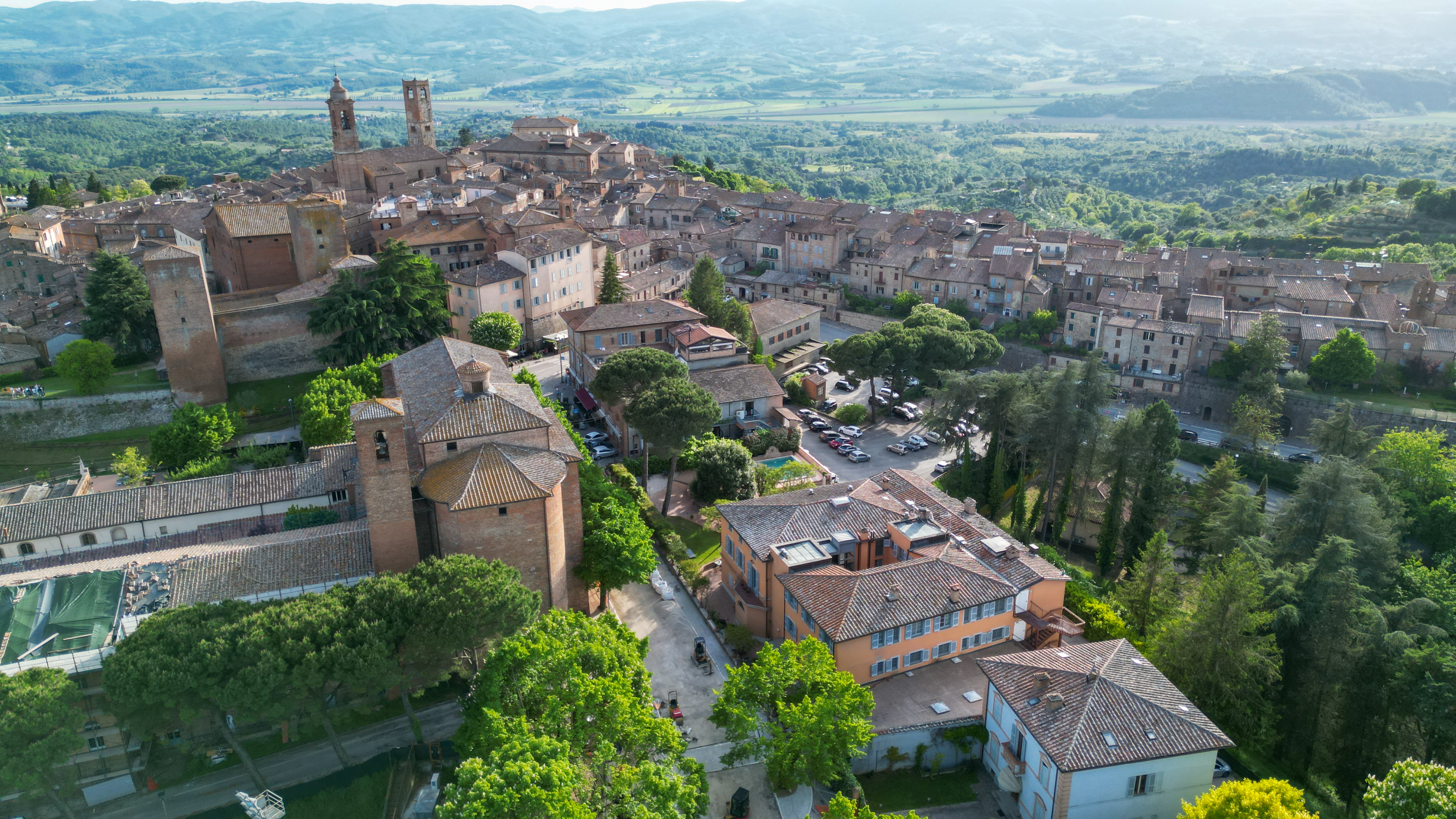 Hotel Vannucci view of Citta Della Pieve from above, showing stone buildings clustered on a hill, looking out onto the green Umbrian countryside