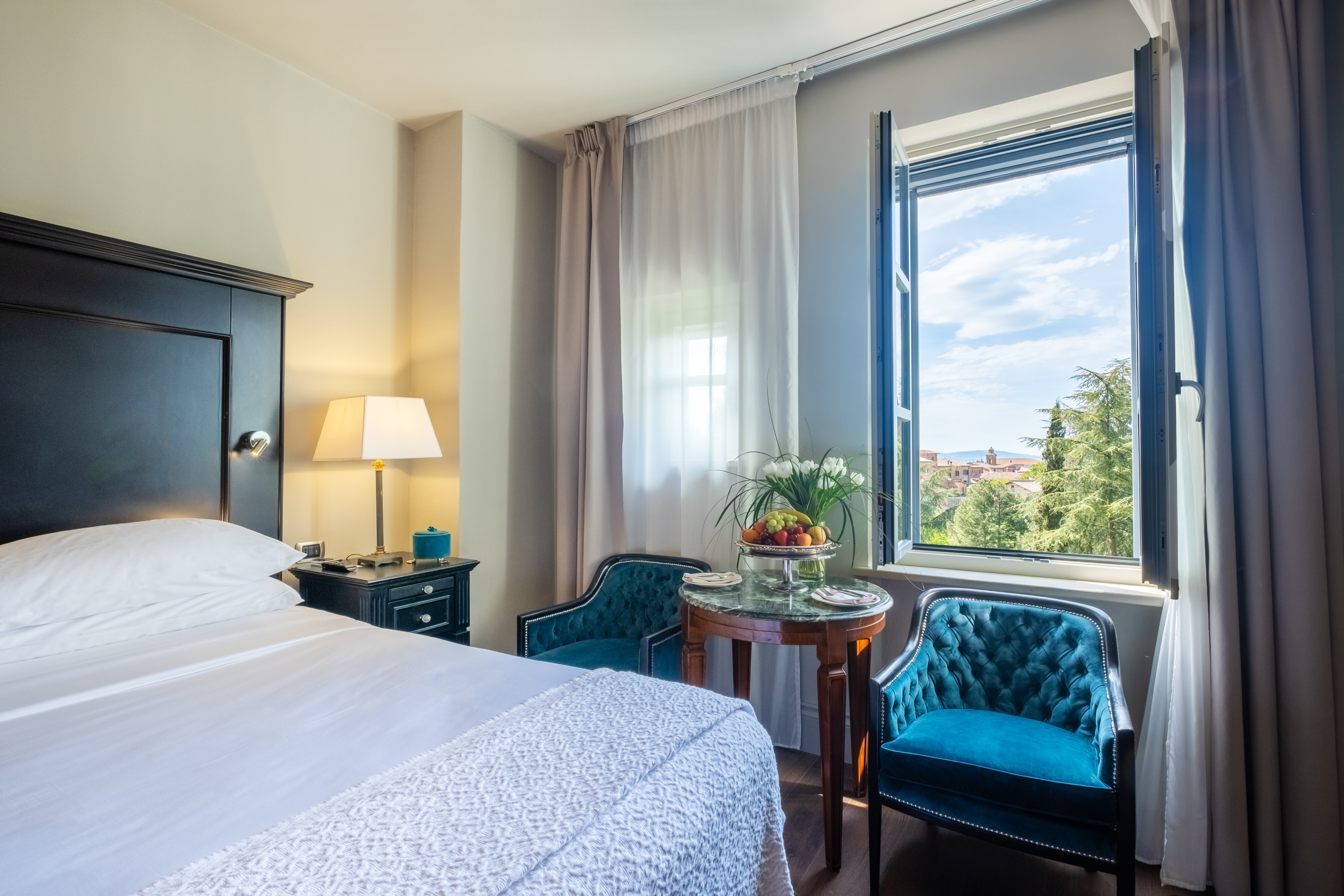 Hotel Vannucci Superior Room with dark wood headboard and ornate blue chair