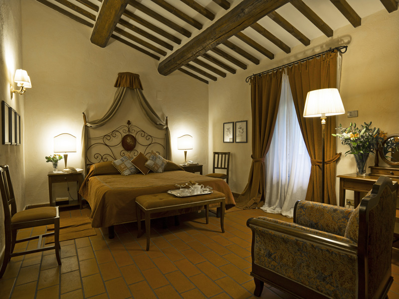Bedroom at the Hotel Villa di Monte Solare with a large bed, draped brown curtains and a brown colour scheme