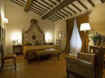 Bedroom at the Hotel Villa di Monte Solare with a large bed, draped brown curtains and a brown colour scheme