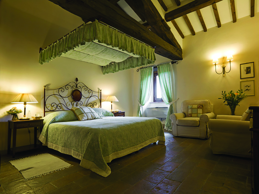 Bedroom at the Hotel Villa di Monte Solare with a large bed, armchairs and green and cream colour scheme