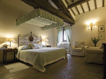 Bedroom at the Hotel Villa di Monte Solare with a large bed, armchairs and green and cream colour scheme