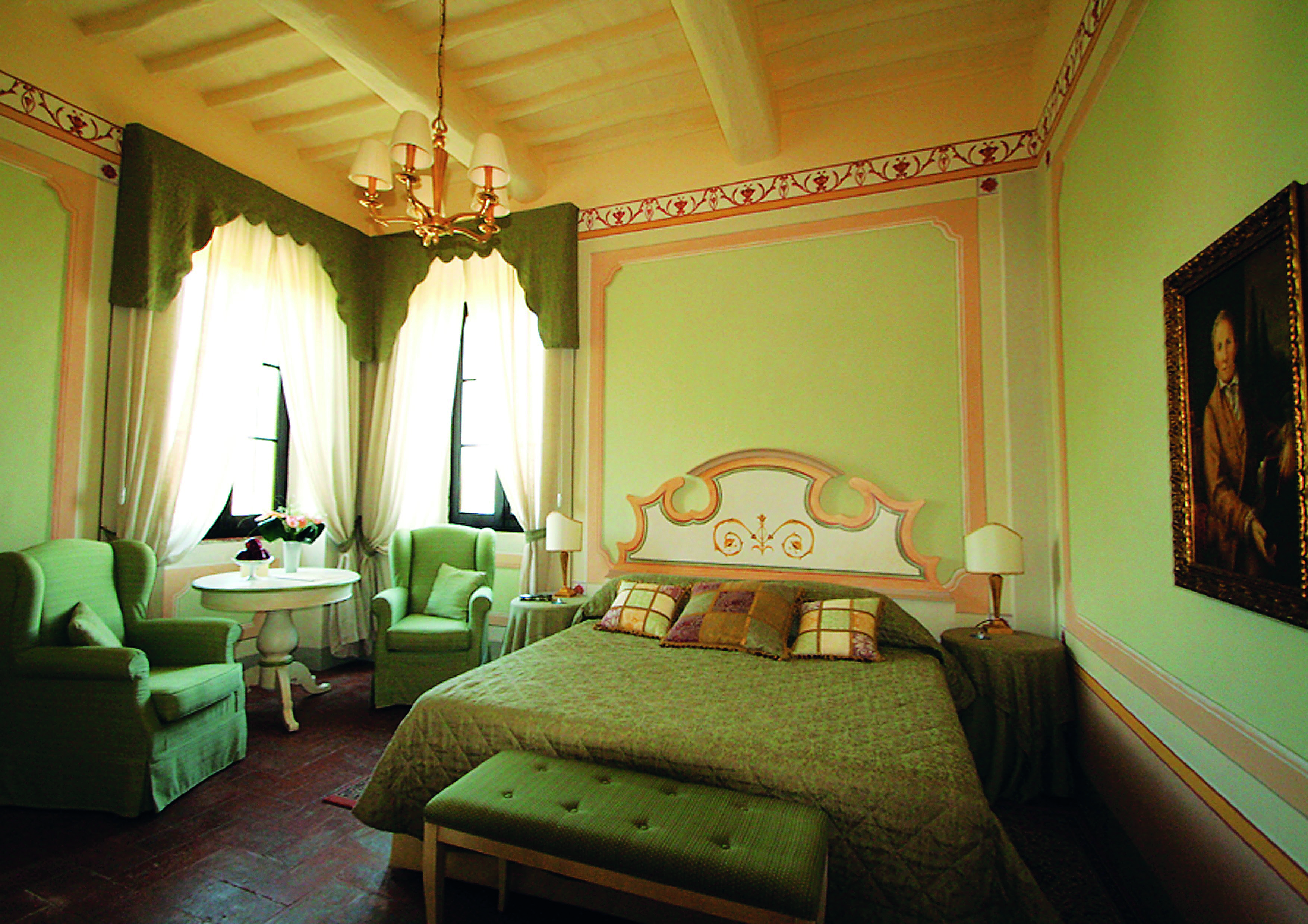 Classic room villa at the Hotel Villa di Monte Solare with a large bed, armchairs and a green colour scheme