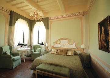Classic room villa at the Hotel Villa di Monte Solare with a large bed, armchairs and a green colour scheme