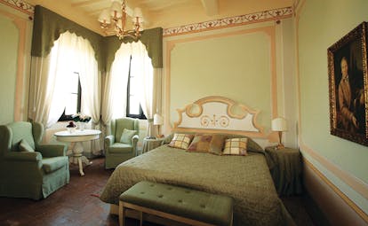 Classic room villa at the Hotel Villa di Monte Solare with a large bed, armchairs and a green colour scheme