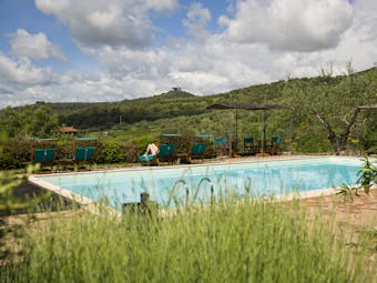 View of the rectangular pool at the hotel villa di monte solare in umbria with green mountains in the background 