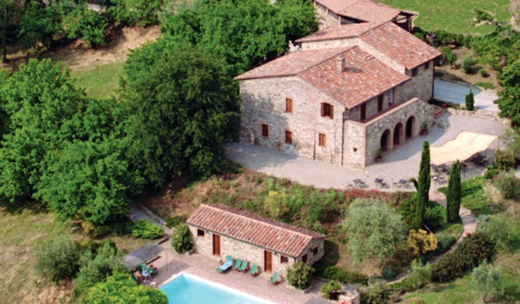 View of the hotel villa di monte solare from above, showcasing the swimming pool and multiple buildings amongst the green countryside