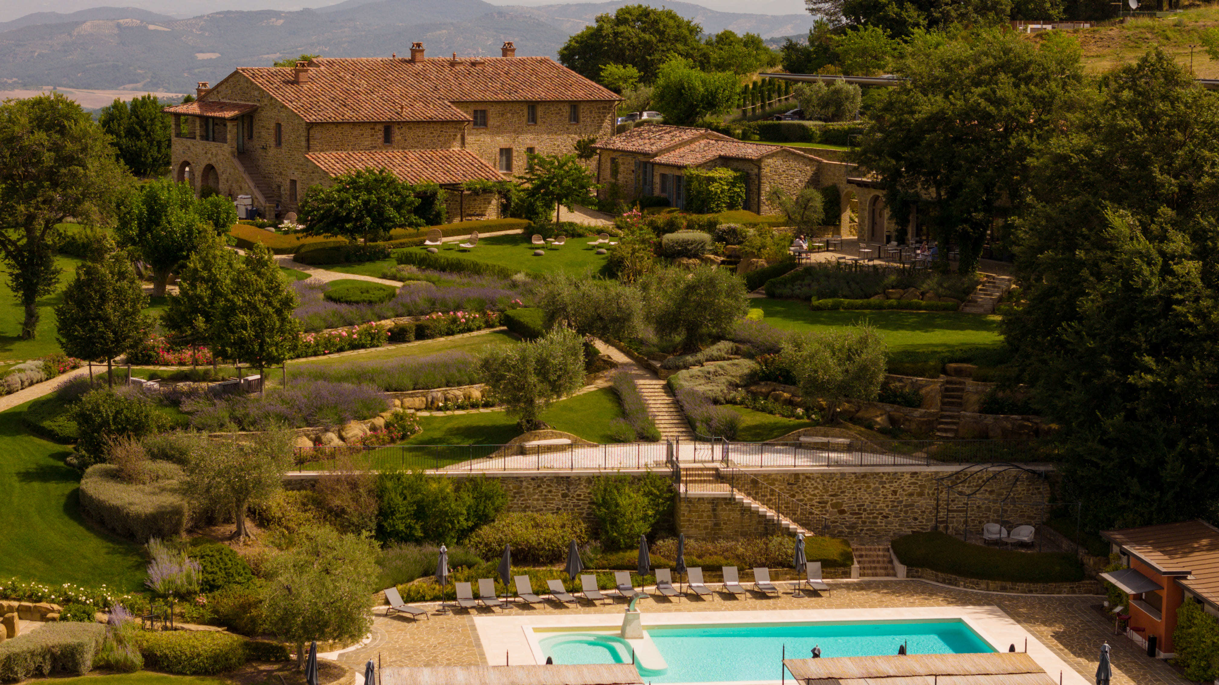 I Borghi Dell'Eremo exterior, showing the tiered gardens leading up from the poolside to the ochre stone hotel building