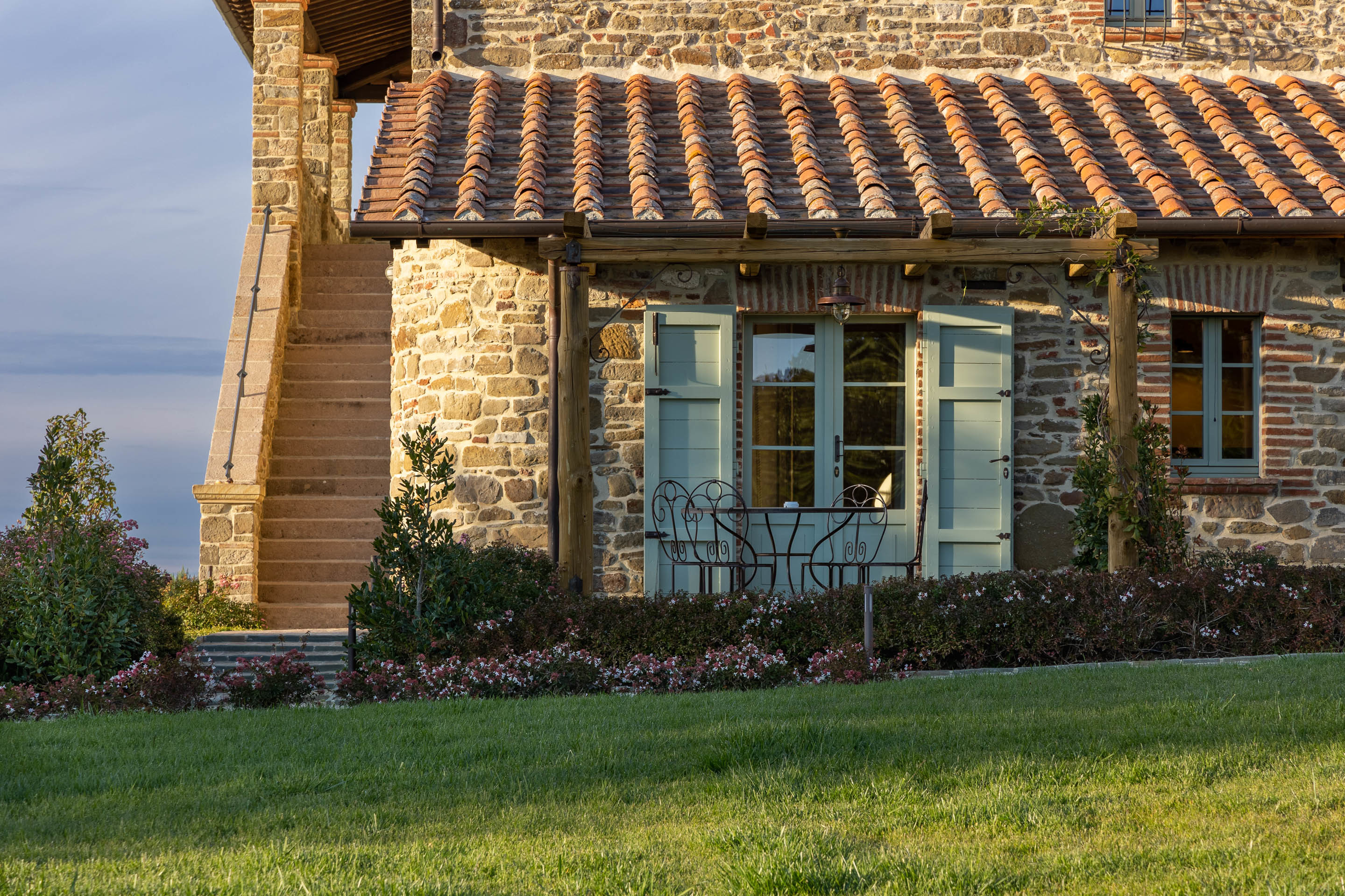 I Borghi Dell'Eremo, the exterior view of a Deluxe Patio Room, with curved terracotta tiled roof, pale sage doors and shutters, and a smattering of plants