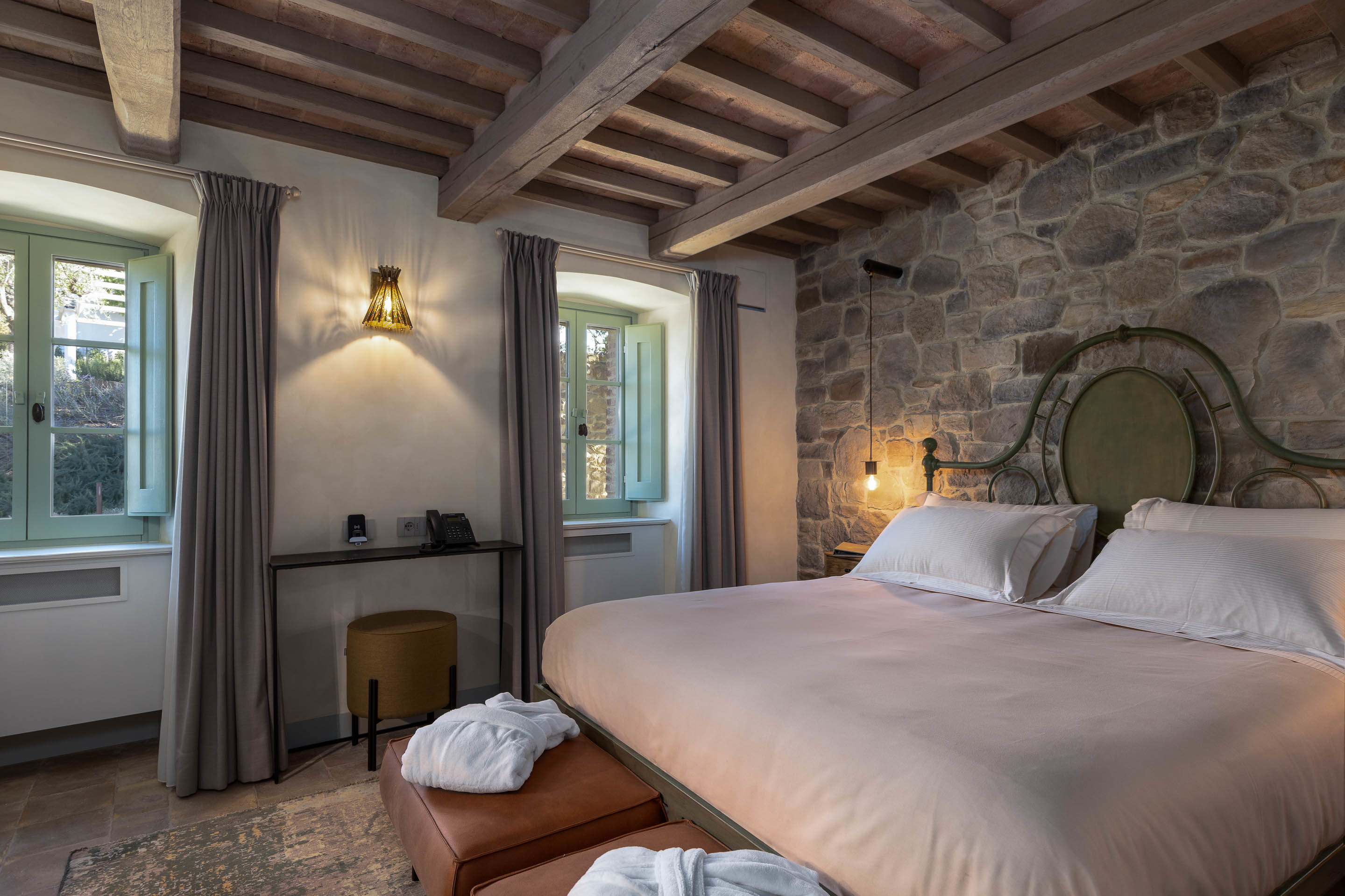 I Borghi Dell'Eremo Superior room, with large double bed, exposed stone walls, beamed ceiling, and a warm neutral colour palette