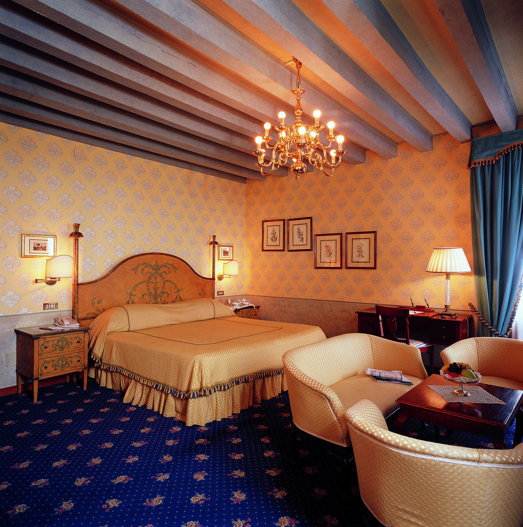 Bedroom with large double bed, chandelier, table and chairs 