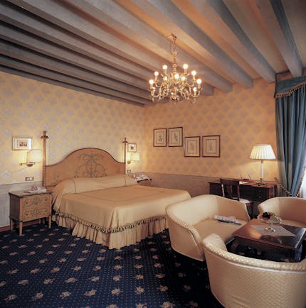 Bedroom with large double bed, chandelier, table and chairs 