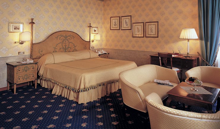 Bedroom with large double bed, chandelier, table and chairs 