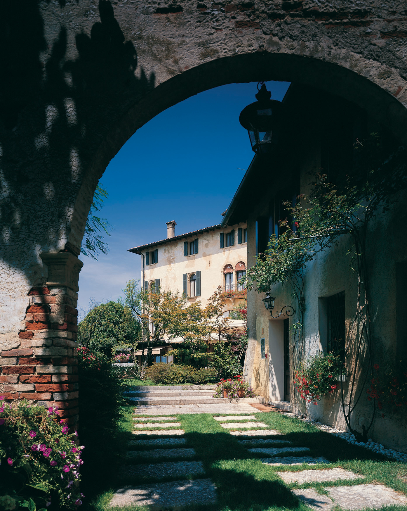 Exterior view of the hotel through an archways showing hotel building with green shutters by windows