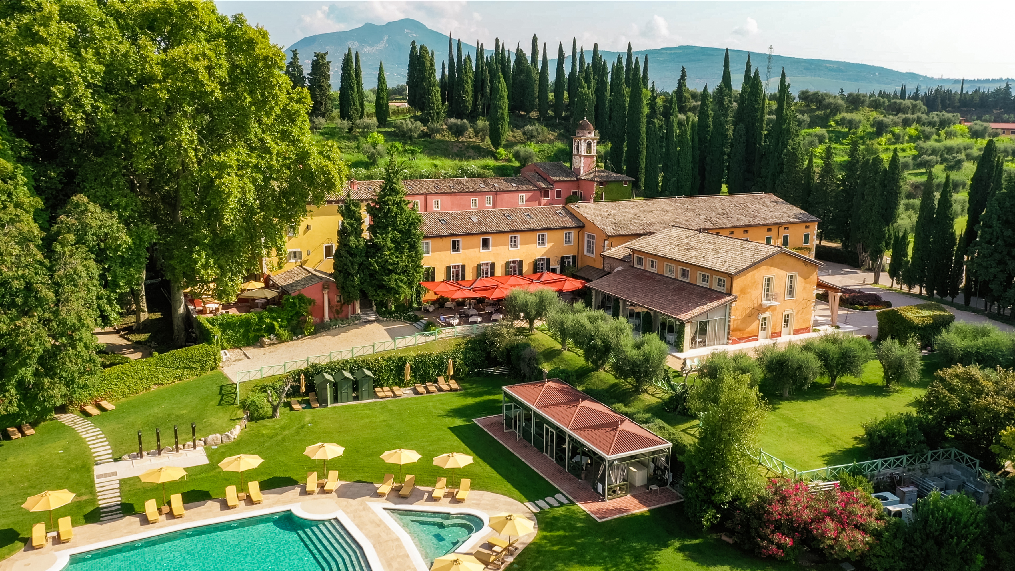 Villa Cordevigo aerial view, looking down on the yellow hotel buildings, the gardens, and the pool