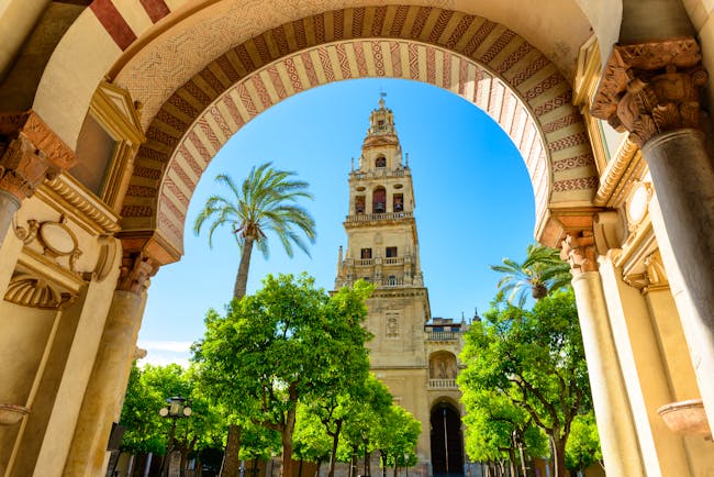 The spire of the Mezquita cathedral in Cordoba seen through an ornate Moorish stone arch