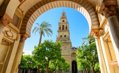 The spire of the Mezquita cathedral in Cordoba seen through an ornate Moorish stone arch